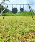 Range setup with AR500 Steel Gong Target 3 Eighths Inch Thick For Precision Shooting, mounted on a tripod in a grassy field.
