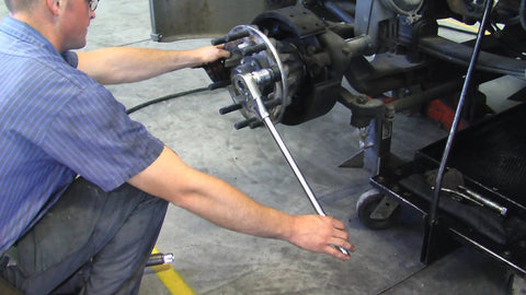 Mechanic using Truck Wheel Stud Installer Tool for 22mm Studs with ratchet on heavy duty vehicle hub in garage