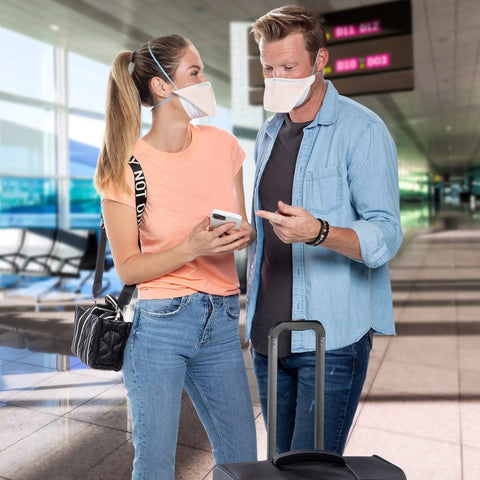Two people wearing N95 Duckbill Respirator Mask For Everyday Use, ASTM Level 3 Protection, Regular Size, Orange, in an airport.