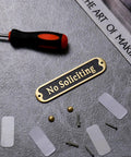 No Soliciting Sign 5 Inch Brushed Matte Brass Finish With Hidden Screws And Nanotape Adhesive shown with installation tools
