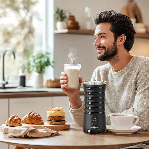 Man enjoying coffee next to 4 In 1 Electric Milk Frother For Hot And Cold Foam, Temperature Control And Auto Shut Off, on kitchen counter.