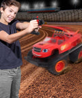 Boy playing with Blaze And The Monster Machines RC Monster Truck Toy For Kids on dirt track under stadium lights