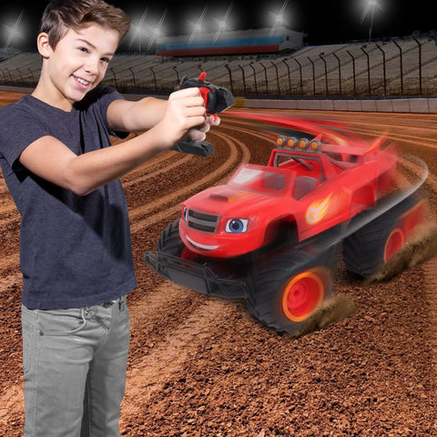 Boy playing with Blaze And The Monster Machines RC Monster Truck Toy For Kids on dirt track under stadium lights