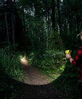 Person using Beast Mode Rechargeable LED Spotlight For Outdoor, Marine, And Emergency Use 1400 Lumens in a forest at night