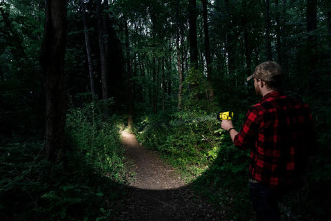 Person using Beast Mode Rechargeable LED Spotlight For Outdoor, Marine, And Emergency Use 1400 Lumens in a forest at night