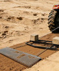 Tow Behind 6 Ft Drag Harrow with chain harrow smoothing dirt, attached to a tractor, for leveling driveways and fields.