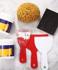 Assortment of drywall repair tools with knockdown texture sponge, two scraper tools, and paint containers on white surface.