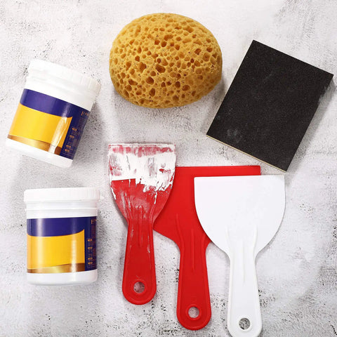 Assortment of drywall repair tools with knockdown texture sponge, two scraper tools, and paint containers on white surface.