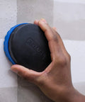 Hand using wallpaper scoring tool with four steel blades, no slip grip, strips and removes wallpaper fast on wall surface.