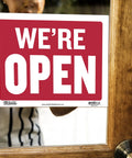 Open And Closed Sign 12x16 Inch Double Sided Vinyl Sign For Storefronts Offices Restaurants Bars Shops Waterproof Indoor Signage With Bold Lettering No Sweat For Window Doors Front Desk And Lobbies 1 Pack showing 'WE'RE OPEN' on door