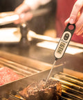 Extra Long 5.6 Inch Stem Digital Thermometer For Meat Frying Grilling Cooking Candy And Kitchen Use With Safe Hands Long Probe Large Clear Display High Contrast Auto Off Black being used on grilled steak