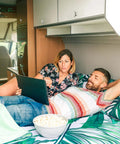 Couple relaxing in RV with a laptop, showcasing living space where a Five Eighth Inch Thumb Operated Offset Cam Lock Latch could be used.