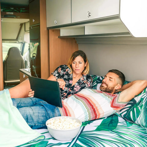 Couple relaxing in RV with a laptop, showcasing living space where a Five Eighth Inch Thumb Operated Offset Cam Lock Latch could be used.