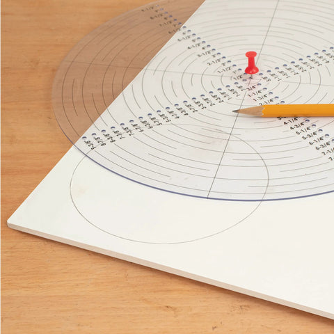 Front view of a 10-inch round clear acrylic center finder compass with black concentric circle marks, pencil nearby.