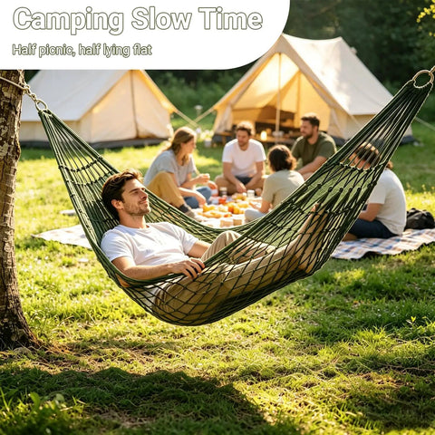 Person relaxing in Breathable Mesh Hammock With Nylon Net For Easy Setup Rope Style Hang Loose Outdoors 98 X 31.5 Inches 100 Kg Capacity Perfect For Camping Backyard Tree Hanging Olive Green near campsite with group in background.