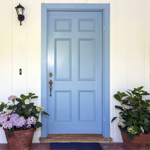 Front view of classic blue door with potted plants, showing where LED Lighted Doorbell Button In Black Plastic can be installed