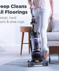 Front-right view of a purple Eureka PowerSpeed upright vacuum cleaner in use on a blue rug.