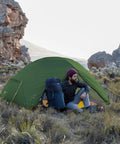 Man sitting by Mongar 2 Person Backpacking Tent for 3 season camping in a rocky landscape.