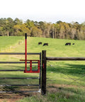 Heavy Duty Steel Gate Latch With Slick Sweep Lever For Ranch And Farm Gates on a wooden post next to grazing cattle.