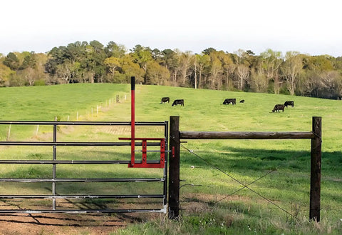 Heavy Duty Steel Gate Latch With Slick Sweep Lever For Ranch And Farm Gates on a wooden post next to grazing cattle.
