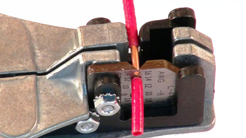 Close-up of Stripmaster Wire Stripper For 10-22 AWG stripping red wire with precision, heavy duty die cast zinc frame visible.