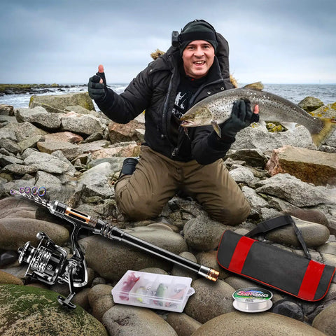 Man holding fish beside Carbon Fiber Telescopic Fishing Rod Kit With Spinning Reel, Line, Lures, Hooks And Carrier Bag For Newbies, Saltwater And Freshwater Angling, 2.1M All In One Gear Set on rocks by the sea.