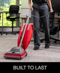 Hardcore Commercial Upright Bagged Vacuum Cleaner With Vibra Groomer Brush Roll, Fifty Foot Power Cord, Six Decked Out Height Settings, Beefy Long Life Motor, And Zero Hassle Shake Out Bags in use on office carpet.