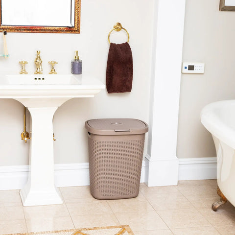 Slim Laundry Hamper With Lid 50L Capacity Clothes Basket In Ivory Plastic With A Wicker Look in a bathroom corner next to a sink