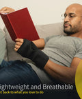 Nighttime Carpal Tunnel Wrist Brace With Cushioned Bead Palm Pillow worn by man reading on couch