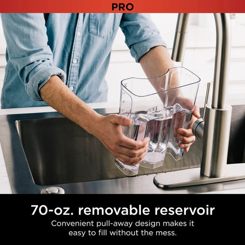 Person filling a clear 70-oz removable reservoir of Programmable XL 14 Cup Barista Grade Coffee Maker Pro at a sink.