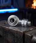 3/4 Inch Steel Heim Joint Rod End With Two Nuts And Right Hand Thread For Quick Installation On Any Ride featuring durable construction on an anvil.
