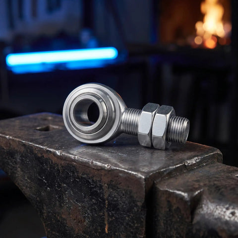 3/4 Inch Steel Heim Joint Rod End With Two Nuts And Right Hand Thread For Quick Installation On Any Ride featuring durable construction on an anvil.