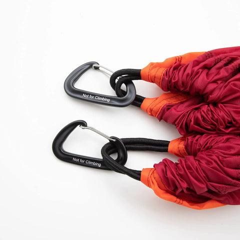 Close-up of red single person camping hammock with durable ripstop fabric and heavy duty straps, includes carabiners, supports up to 300 lbs.