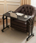 Overbed Laptop Desk With Wheels, Adjustable Height And Length Bed Tray Cart For Hospital Or Home Use, Mobile Bedside Table On Casters With A Sturdy Wood And Steel Frame For Easy Glide And Reliable Support next to a leather chair with a laptop and cup displayed