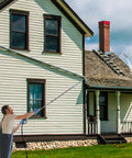 Person using Heavy Duty Pressure Washer Extension Wand Set 9 Pack With 30 90 And 120 Degree Curved Wands on house siding at height.