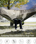 Person relaxing in Camping Hammock With Net And Rain Fly Portable Lightweight Outdoor Hammock Tent Kit in nature.