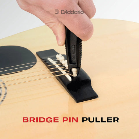 Pro-Winder All-In-One Guitar Tool With String Winder Cutter Bridge Pin Puller close-up on acoustic guitar bridge