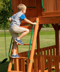 Child climbing ladder on Skyfort II Cedar Wood Swing Set With Wave Slide, Raised Clubhouse, Crow's Nest, outdoor playset.