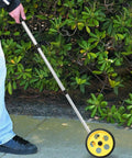 Baxnore 8 Inch Measuring Wheel with 0 9999.9 Meter Telescopic Pole being used on a path surrounded by green foliage.