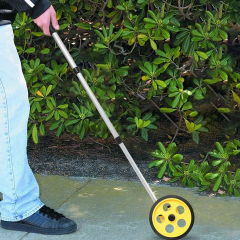Baxnore 8 Inch Measuring Wheel with 0 9999.9 Meter Telescopic Pole being used on a path surrounded by green foliage.