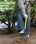 Person using Heavy Duty Garden Fork 45 Inch Pitch Fork With Steel Tines And Comfortable Y Grip For Spading Digging Compost And Lawn Bed Work Four Metal Tines For Tough Soil in a garden.