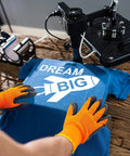 Person using 3 Pairs Heat Resistant Gloves For Heat Press And Sublimation Transfer Printing Orange And Black Durable Polyester Comfort Fit For 3D Vacuum Transfer Machines And Everyday Work handling a t-shirt under a heat press machine