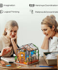 Mother and daughter assembling DIY Miniature Greenhouse Kit With Dope LED Lights 1 To 24 Scale Wooden Dollhouse at table.