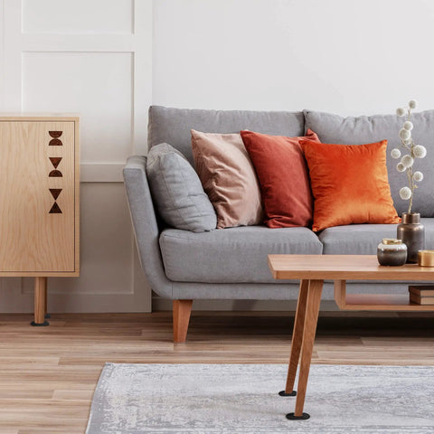 Modern living room with a gray sofa, orange and beige cushions, light wooden coffee table and cabinet, decorated with vases.