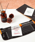 12 Inch Titanium A4 Paper Cutter With Automatic Safety Guard And Side Ruler on desk with pinecones and paper