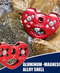Red Zipline Pulley 25KN Aluminum Alloy Trolley With Stainless Steel Bearings on rocky surface, featuring holes and logo engraving.