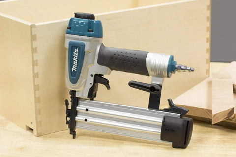 Rock Solid 18 Gauge 2 Inch Brad Nailer Kit positioned beside a wooden box, showcasing toolless jam clearing and rubber nose.