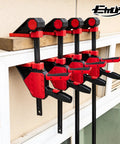Heavy Duty Twenty Four Inch Bar Clamps Set With Five Hundred Fifty Pound Rock Solid Grip For Woodworking And Carpentry mounted on a wall.