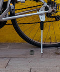Thru Axle Nut For Bicycle M15x1.5mm Aluminum Alloy Rear Fork Axle Nut With Easy Installation beside bike on pavement.