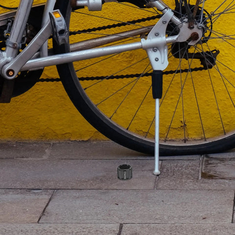 Thru Axle Nut For Bicycle M15x1.5mm Aluminum Alloy Rear Fork Axle Nut With Easy Installation beside bike on pavement.